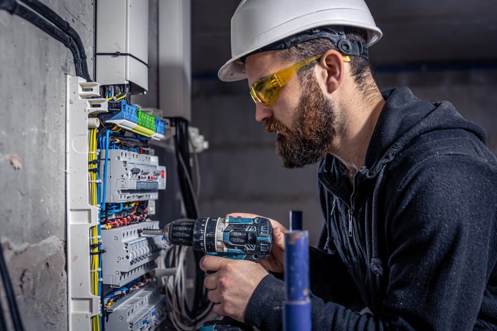 Electrician installing wiring and components inside a commercial electrical panel
