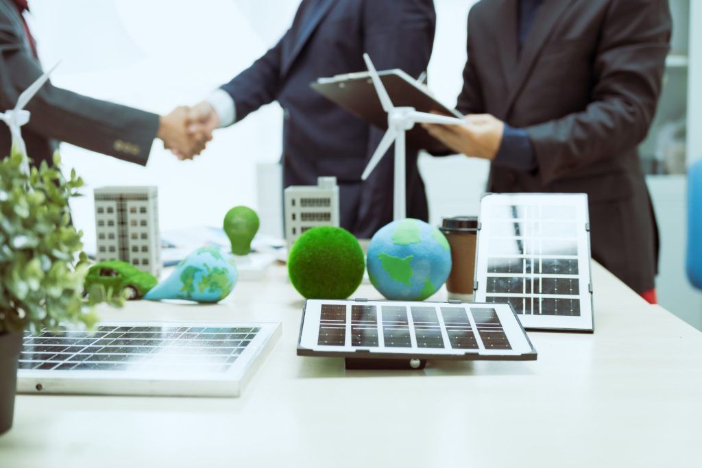 Business meeting discussing renewable energy solutions with solar panels and wind turbines