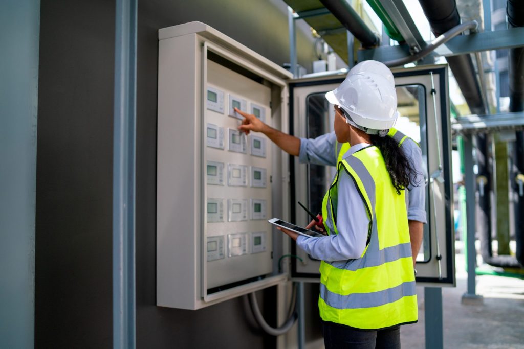 Engineer inspecting commercial electrical control panel during system optimisation